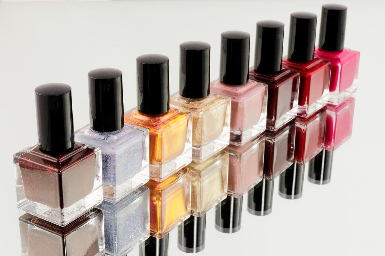A row of nail polish bottles from nude and peach to berry red