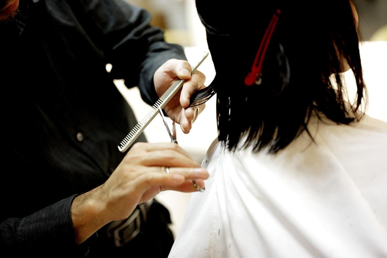 Stylist cutting a guest’s dark hair with scissors and comb