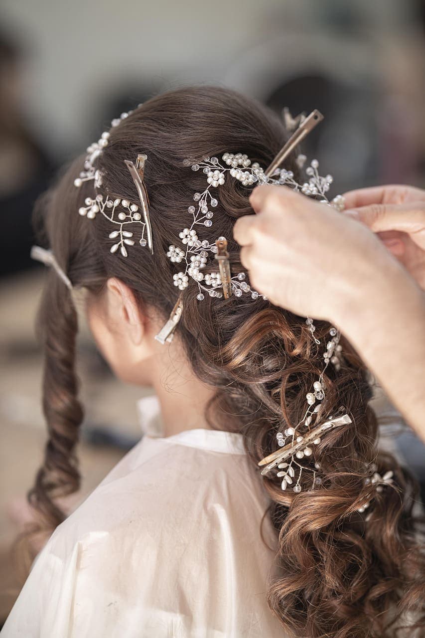 Stylist pinning a low bridal knot dressed with pearl sprigs
