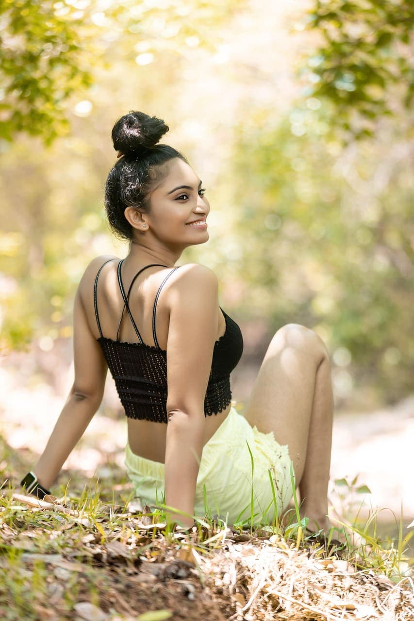Priya Raman sitting on a grassy bank, smiling over her shoulder