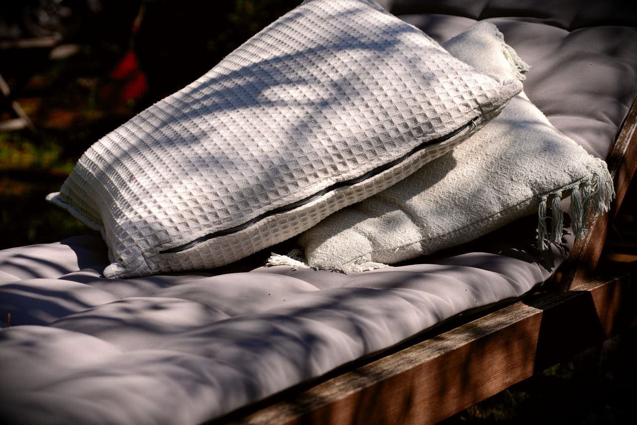 A cushioned lounger with a waffle-weave pillow in deep shade